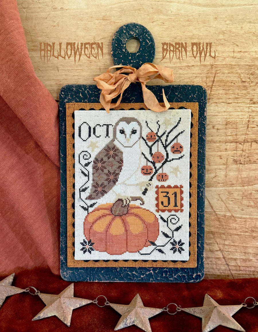 Halloween-themed cross-stitch design with an owl and pumpkin on a wooden background.