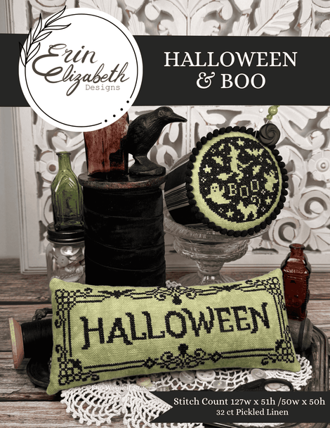 Cross-stitch pattern cover for 'Halloween & Boo' by Erin Elizabeth Designs, featuring a completed light green and black cross-stitched pillow with 'HALLOWEEN' stitched on it, styled with vintage props on a rustic table.