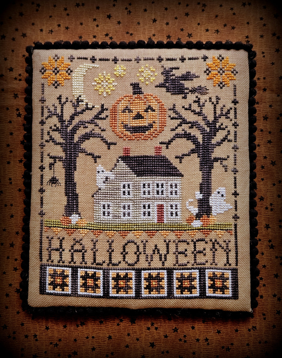 Halloween-themed cross-stitched design with a pumpkin, house, and ghosts on a brown background.