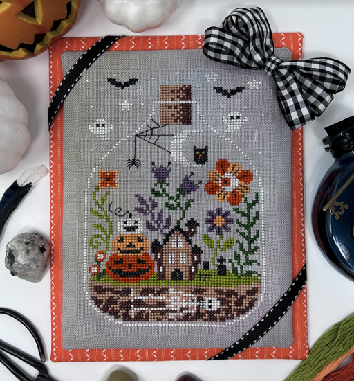 Cross-stitched Halloween design with pumpkins, ghosts, and bats on a white background.