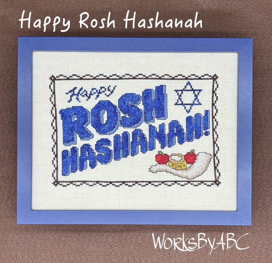A framed cross-stitch design with the words 'Happy Rosh Hashanah!' in blue, a blue Star of David, and small Passover symbols on a white fabric background, set against a brown backdrop. White text at the top reads 'Happy Rosh Hashanah' and 'WorksByABC' appears at the bottom.