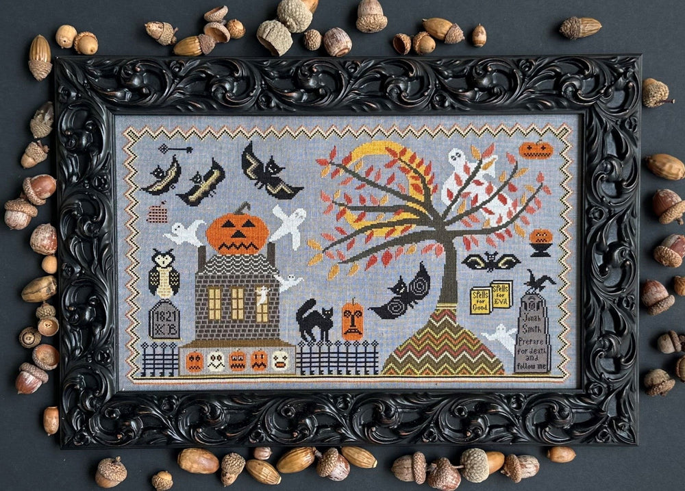 Framed Halloween-themed cross-stitch pattern with decorative elements on a dark background.