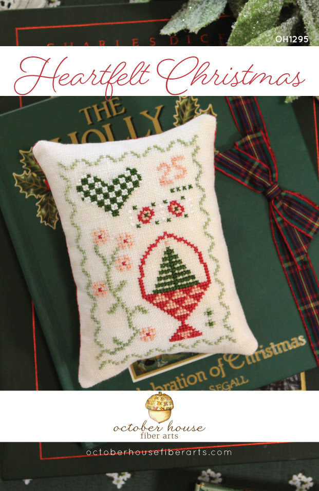 Cross-stitched Christmas pillow on a green book with decorative elements