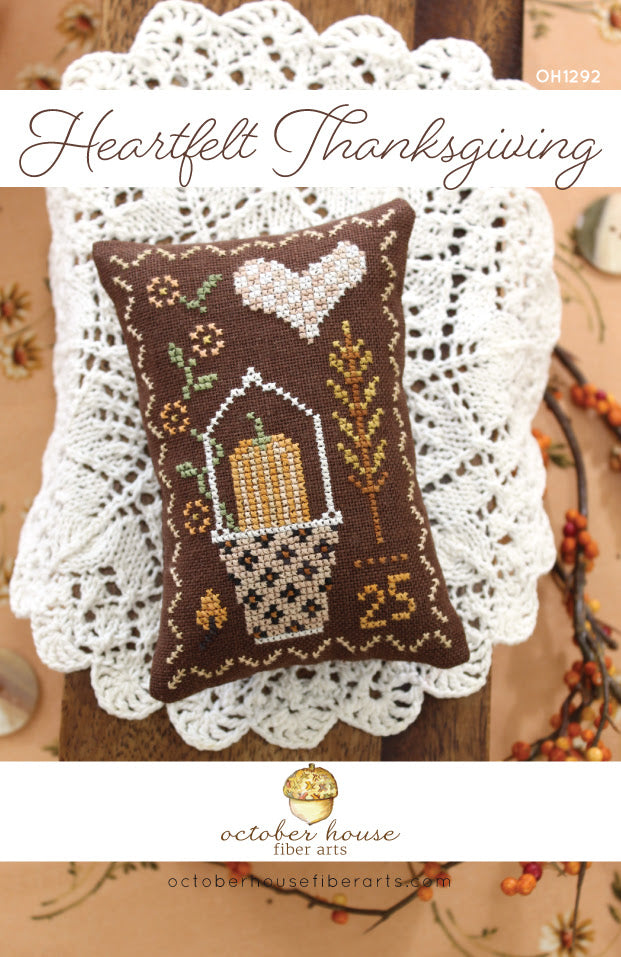 Cross-stitched pillow with autumn design on a lace doily, featuring 'Heartfelt Thanksgiving' text.