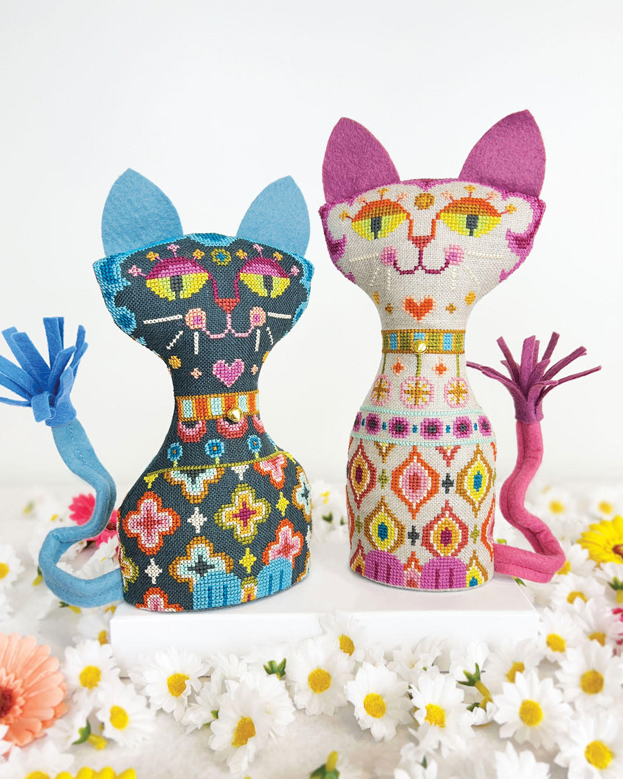 Two cross-stitched cat toys on a white background with flowers.