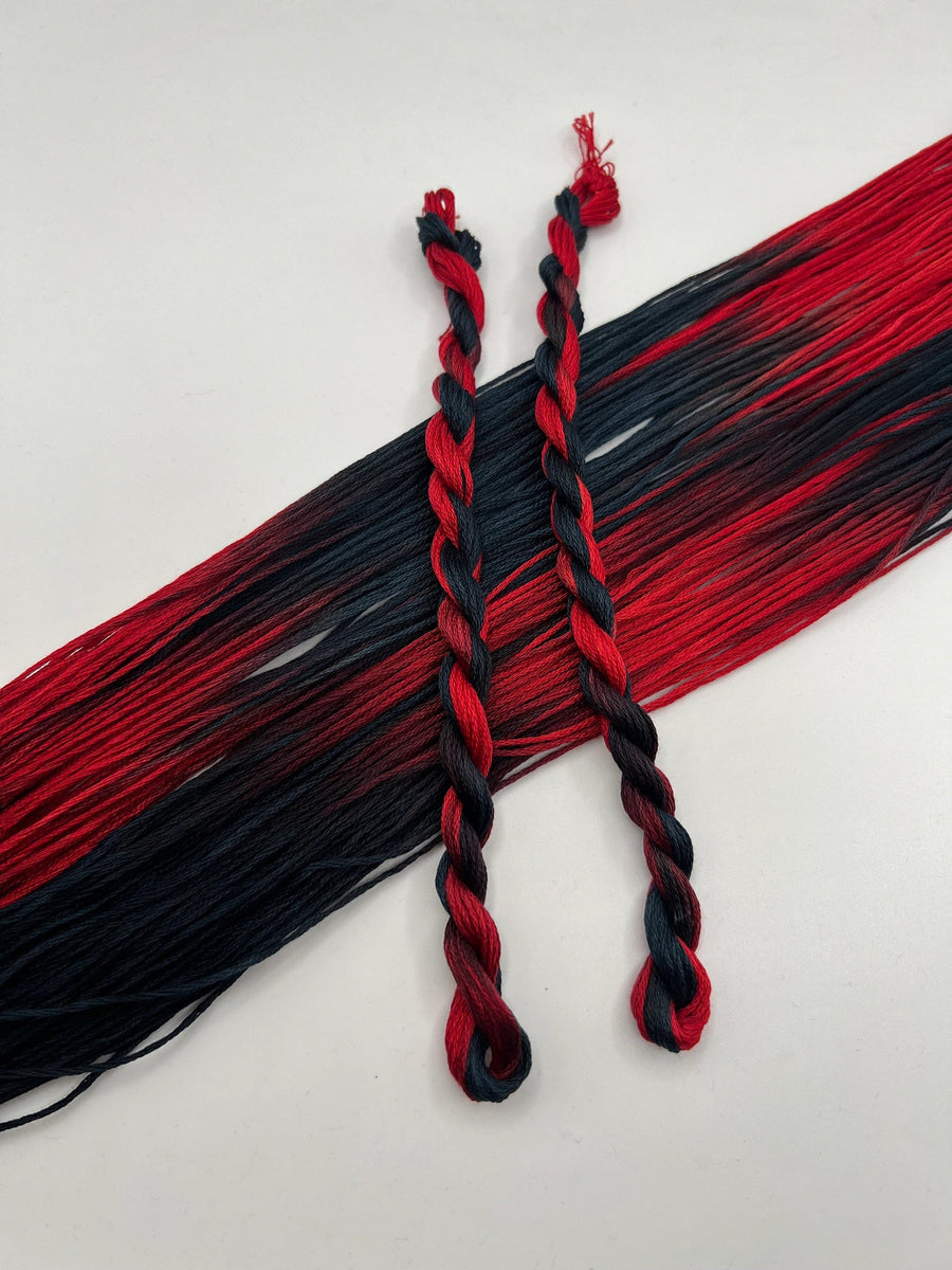 Two braided red and black strings on a white background