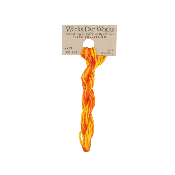 A single skein of Weeks Dye Works 'Flower Collection' cotton thread in the shade 'Hot Rod', featuring a twisted blend of vibrant orange and yellow fibers, attached to its original kraft paper packaging header card against a plain white background.