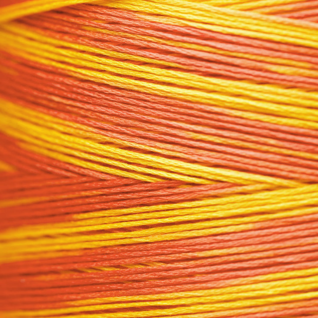Close-up of a wound spool of variegated thread with alternating stripes of orange, red, and yellow.