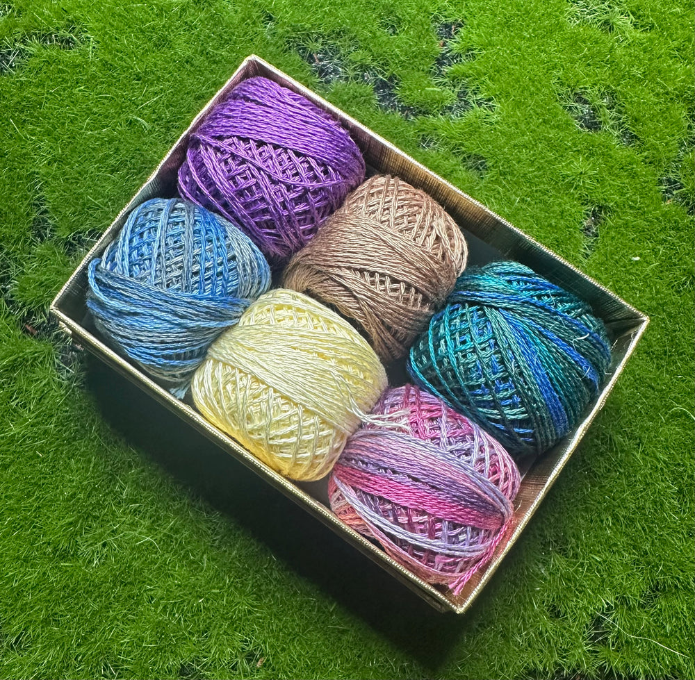 Box of colorful thread balls on a grassy background