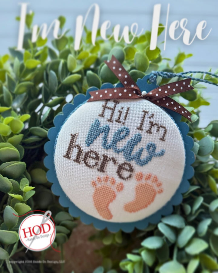 Decorative sign with 'Hi, I'm new here' text and footprints on a green leafy background.