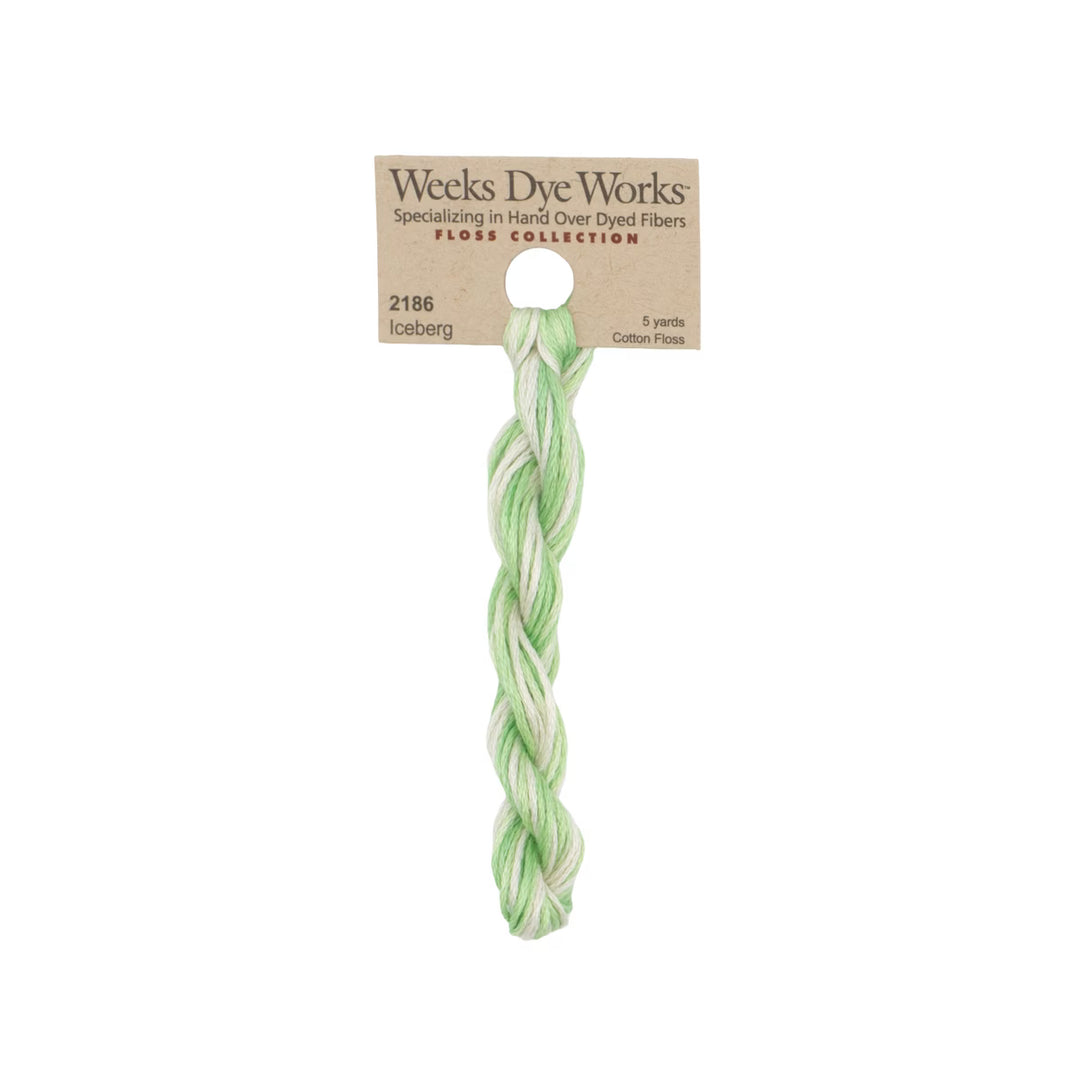 A single cotton embroidery thread skein from Weeks Dye Works, featuring a light green and white variegated pattern, attached to its original kraft paper packaging label.