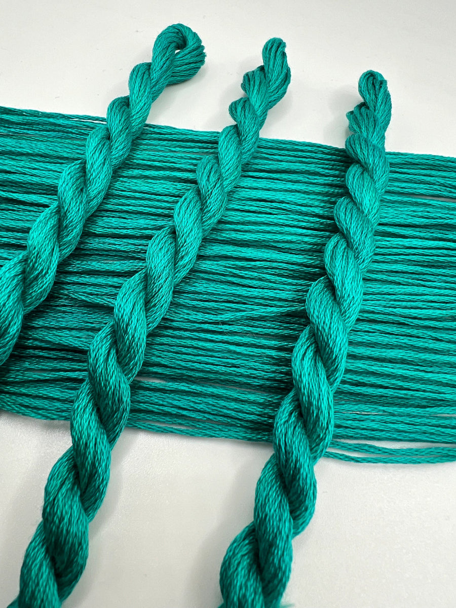 Turquoise thread with braided strands on a white background