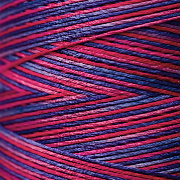Close-up of variegated yarn with alternating stripes of bright pink, deep red, and dark purple.