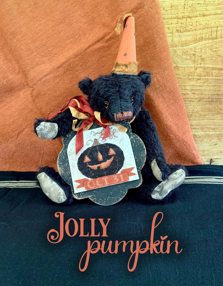 Black teddy bear with a pumpkin label and gold hat on a blue surface, with 'Jolly Pumpkin' text.