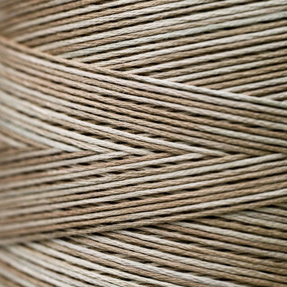 A close-up texture shot of braided twine or cord in a variegated light brown and beige color, arranged in a herringbone pattern.
