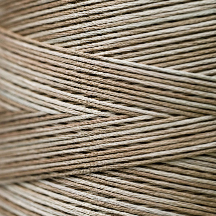 A close-up texture shot of braided twine or cord in a variegated light brown and beige color, arranged in a herringbone pattern.