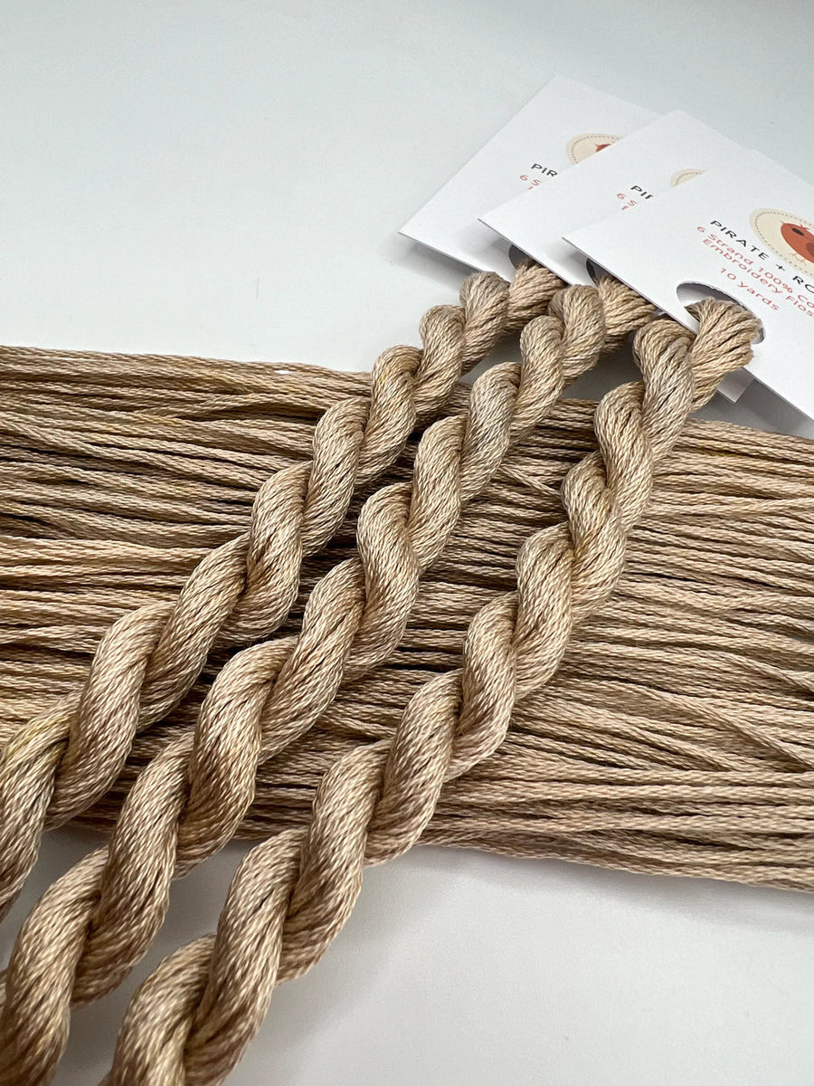 Three braided ropes of skeins of light brown thread  on a white background with a product label.