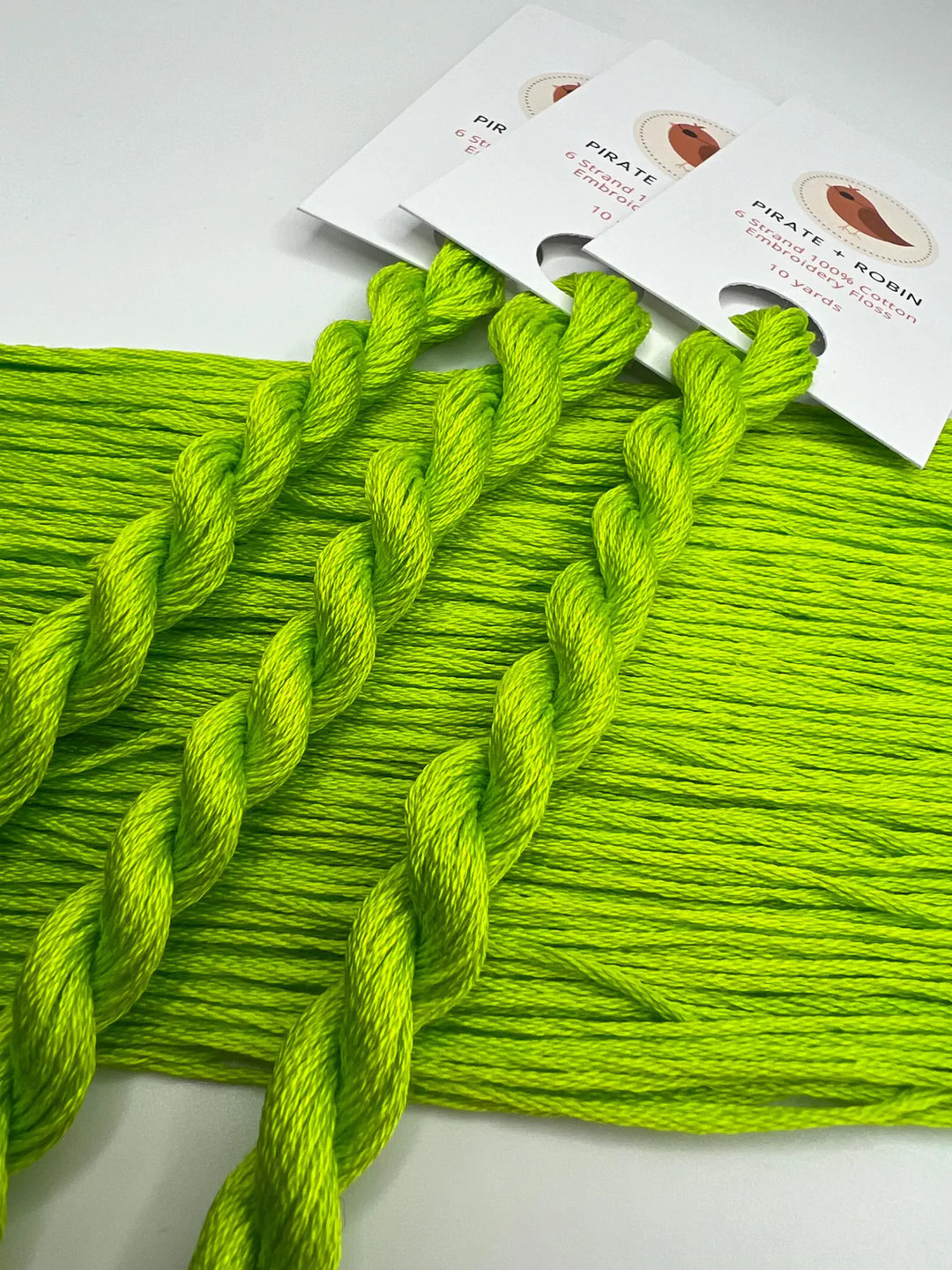 Neon green yarn skeins on a white background with product packaging.