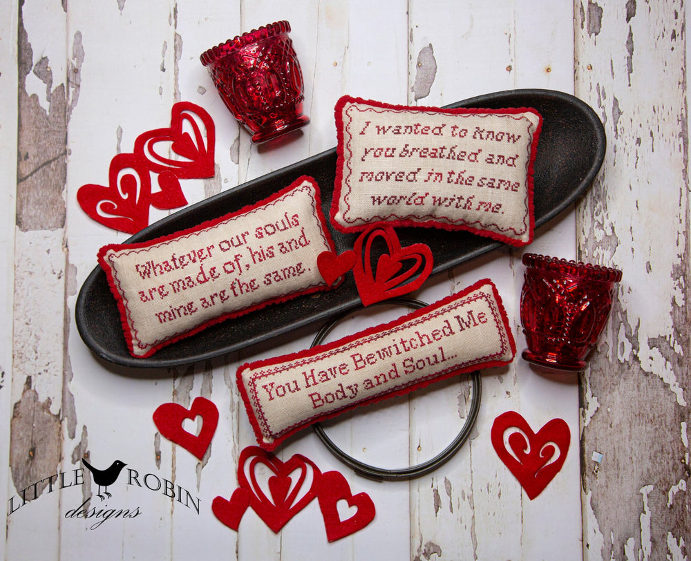 Decorative pillows with text and red heart-shaped objects on a rustic wooden surface.