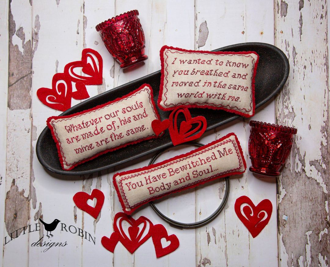 Decorative pillows with text and red heart-shaped objects on a rustic wooden surface.