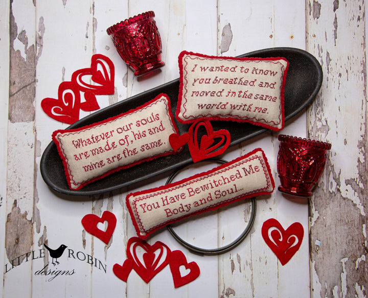 Decorative pillows with text and red heart-shaped objects on a rustic wooden surface.