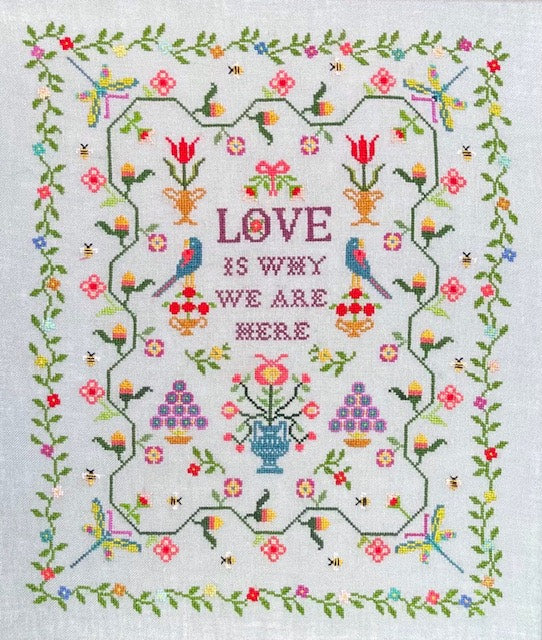 Cross-stitched Sampler with floral design and 'Love is why we are here' text