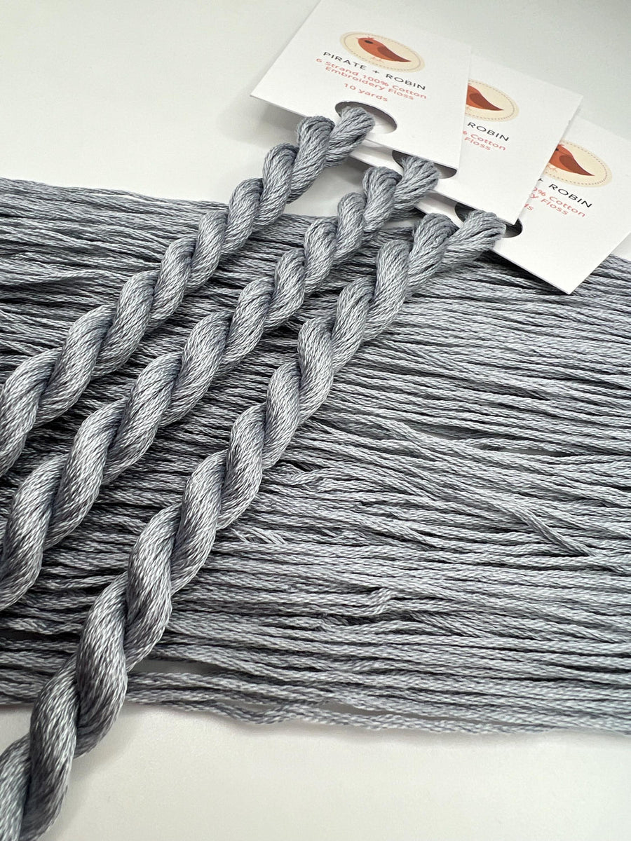Gray yarn skeins with a brand tag on a white background