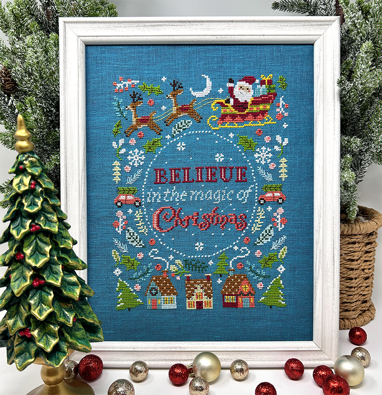 Framed cross-stitched artwork with Christmas-themed design and 'Believe in the magic of Christmas' text, surrounded by festive decorations.