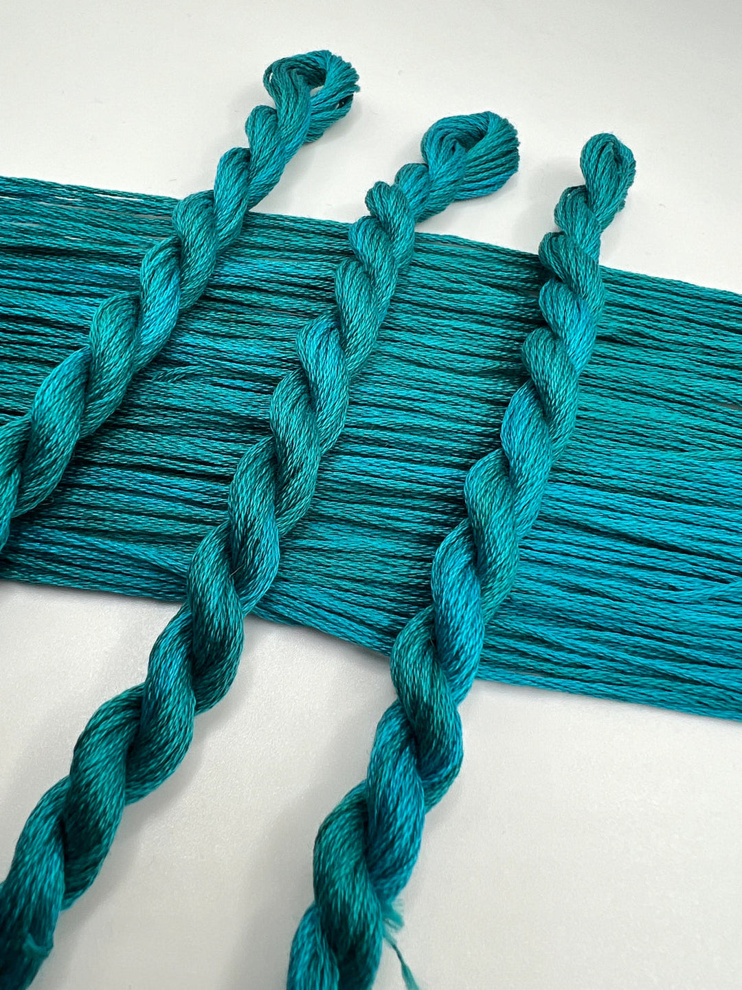 Turquoise thread  with braided ends on a white background