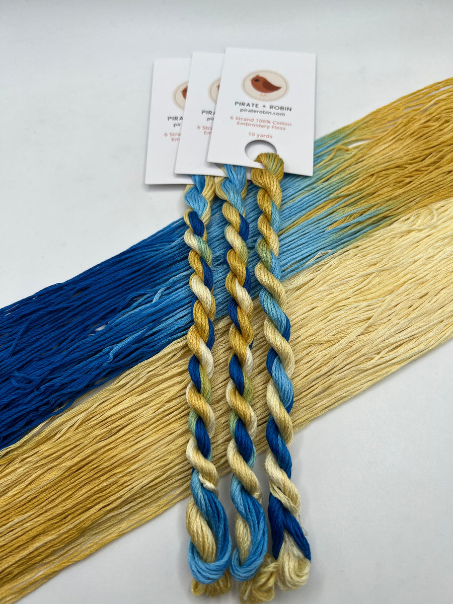 Two braided yarn samples in blue and yellow with tags on a white background