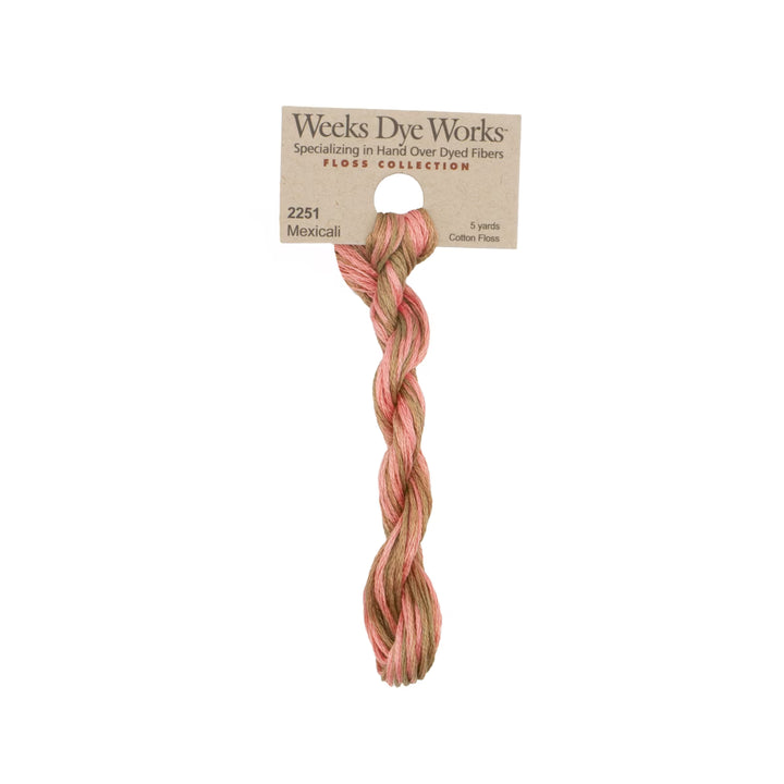 A single twisted bundle of Weeks Dye Works cotton fiber yarn in the Mexicali shade, featuring a variegated pattern of dusty pink and light tan. The yarn is attached to a kraft paper header card with product details, set against a plain white background.
