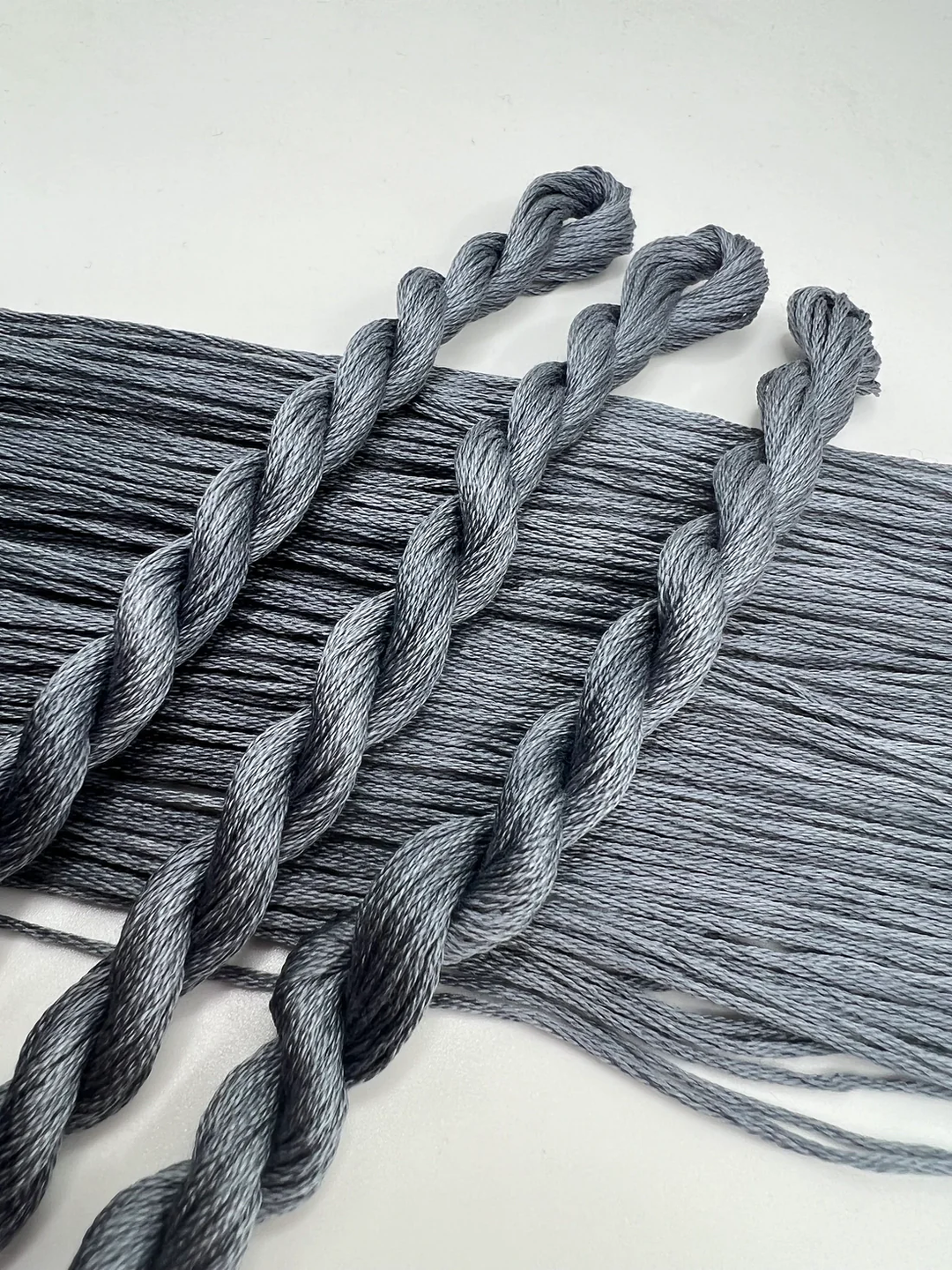Gray braided embroidery floss skeins on a white background