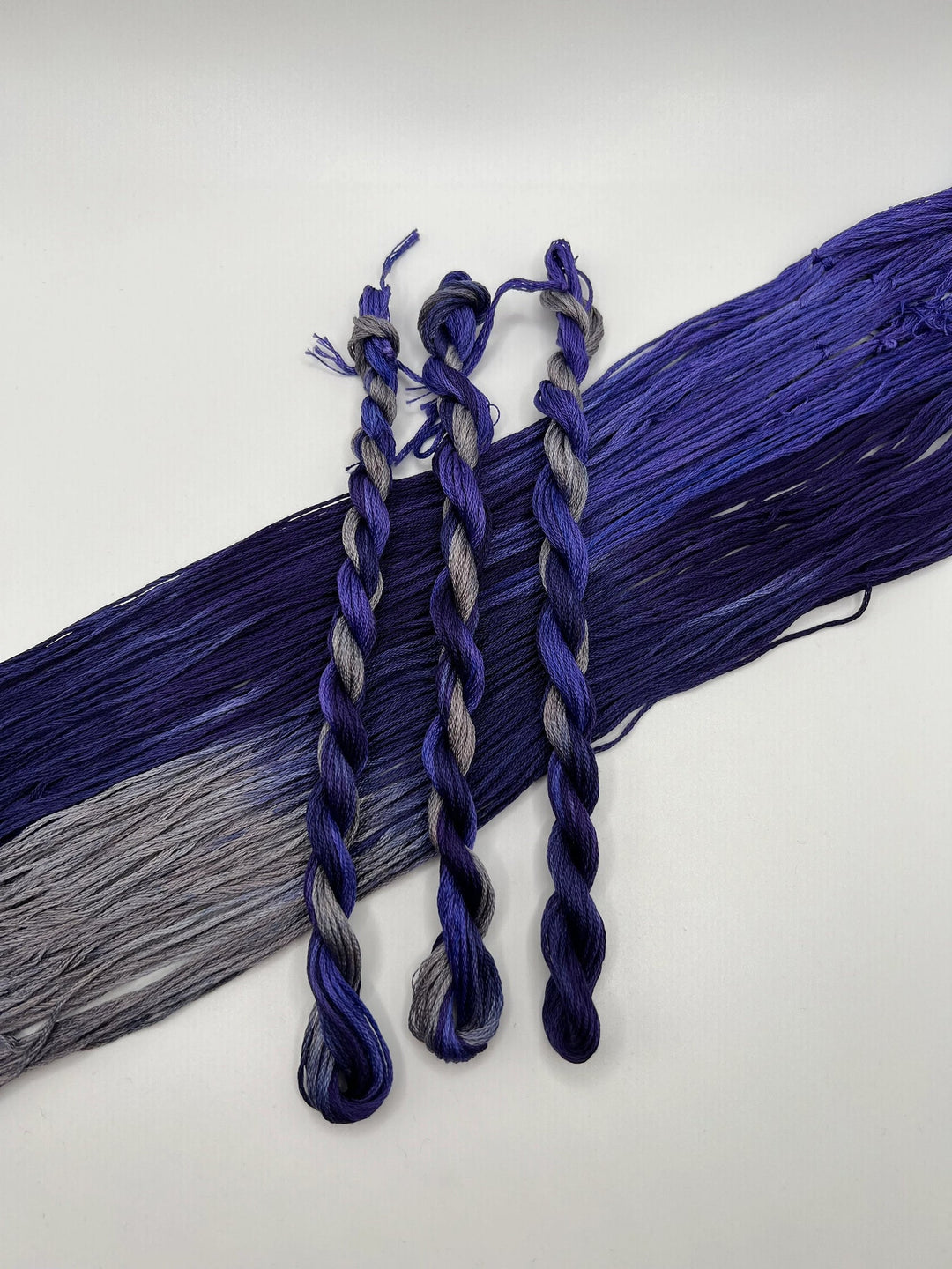 Two braided hair extensions in blue and gray on a white background