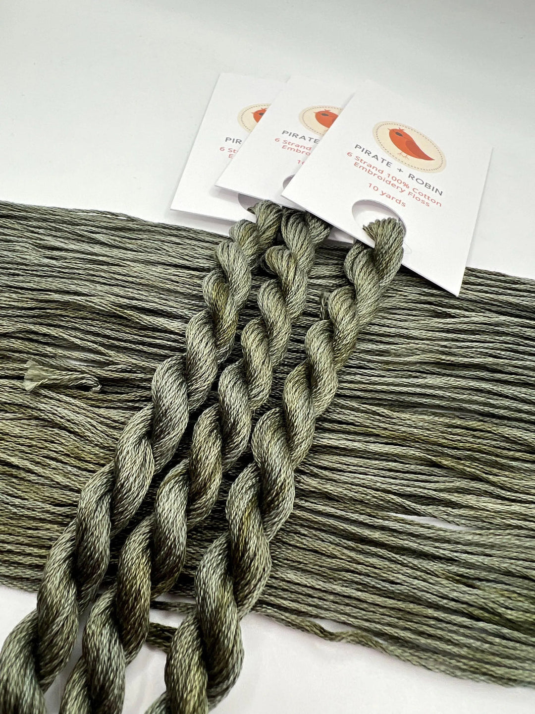 Green thread skeins with brand labels on a white background