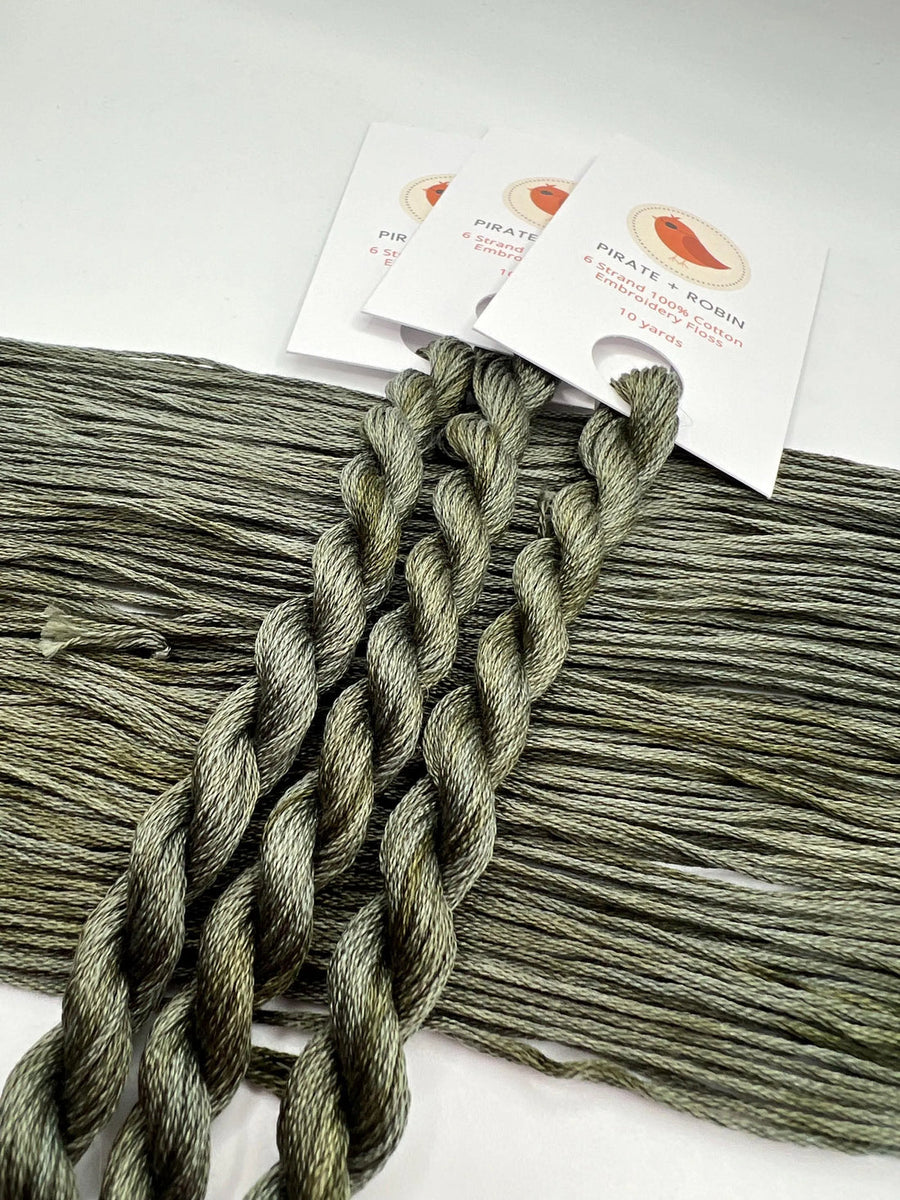 Green thread skeins with brand labels on a white background