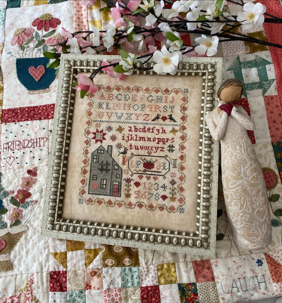 Decorative cross-stitched sampler with floral and fabric background