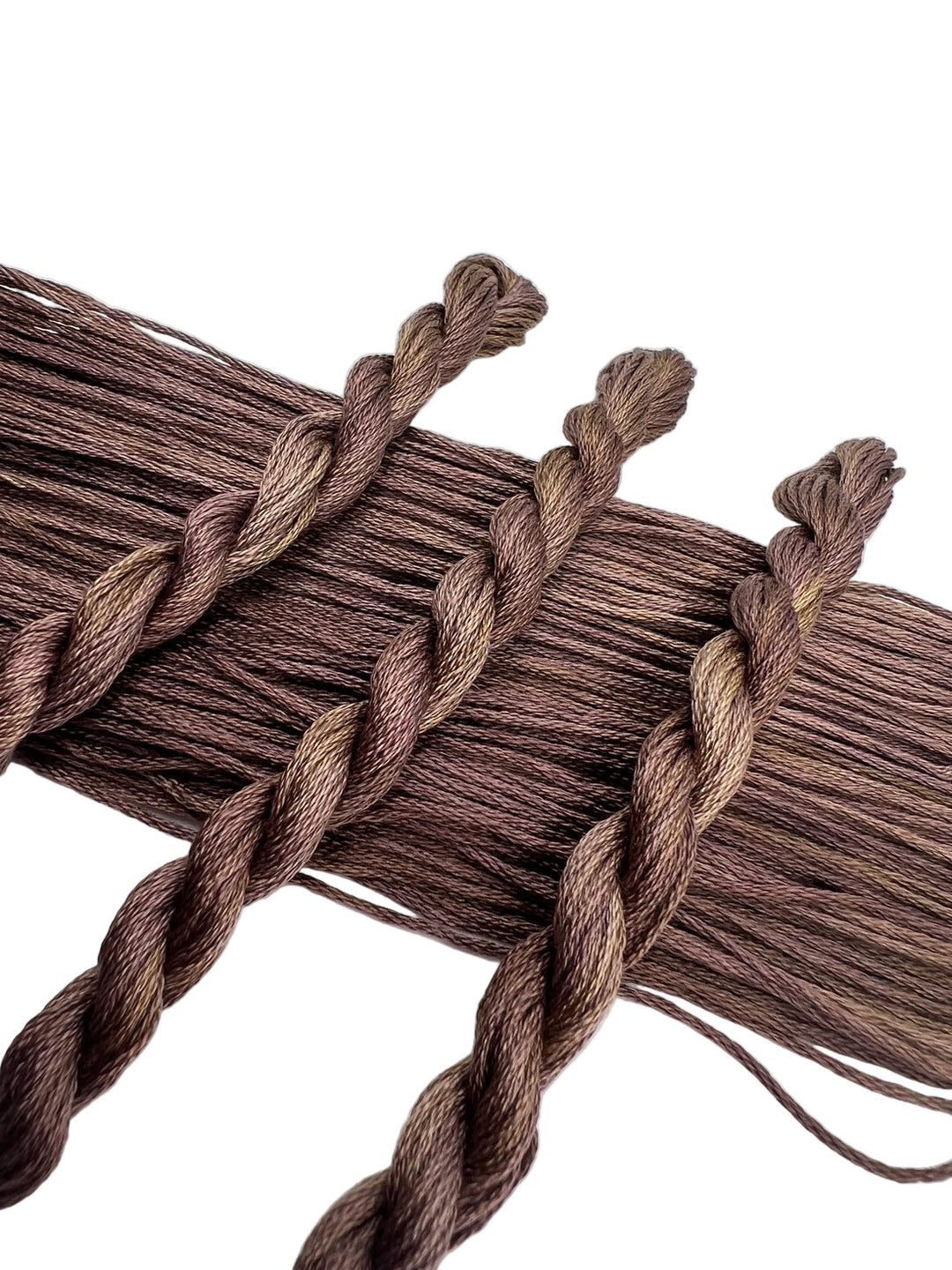 Brown yarn skeins braided together on a white background