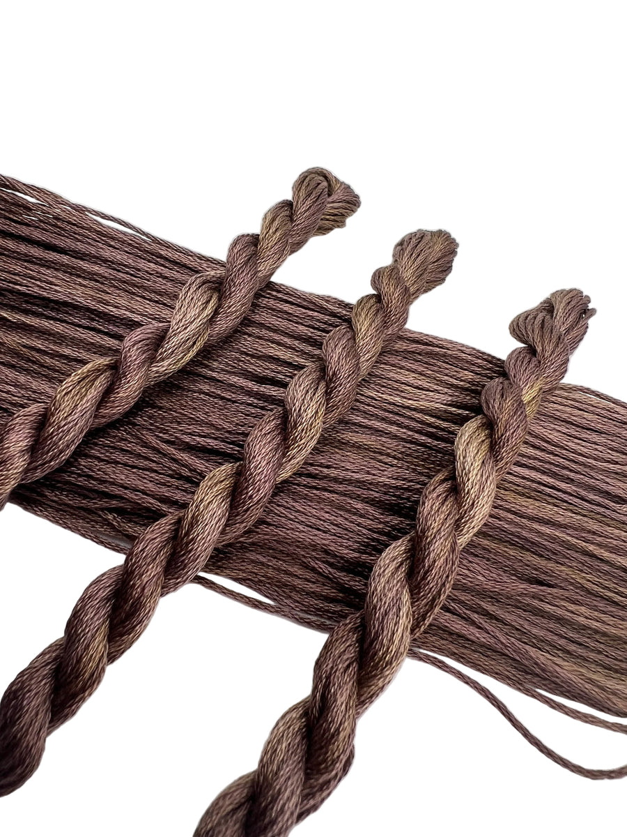 Brown yarn skeins braided together on a white background