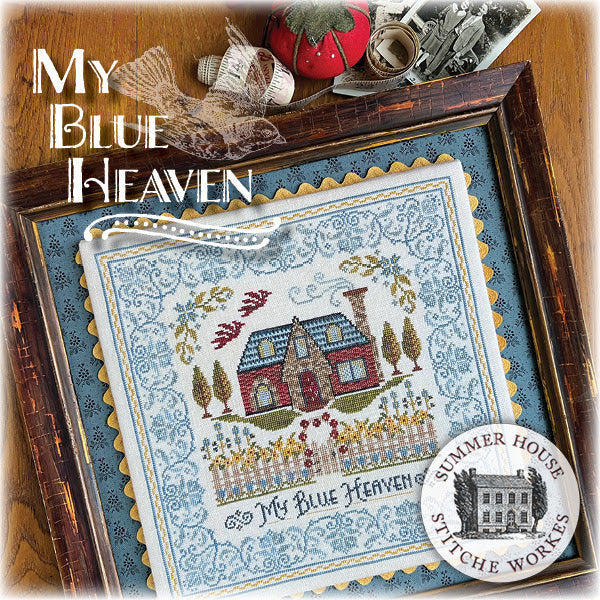 Cross-stitched piece with 'My Blue Heaven' text and 'Summer House Stitche Works' logo, framed with decorative items.