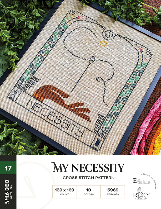 Cross stitch pattern with a design of a hand holding a heart and the word 'Necessity', surrounded by greenery and embroidery floss.