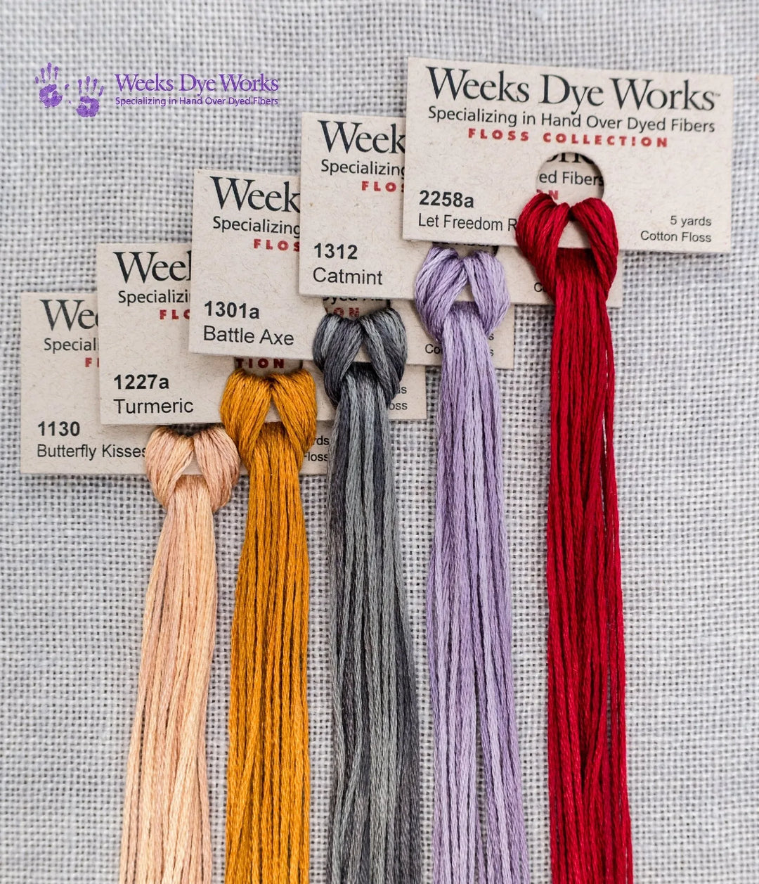 Collection of Weeks Dye Works embroidery floss with color labels on a textured background