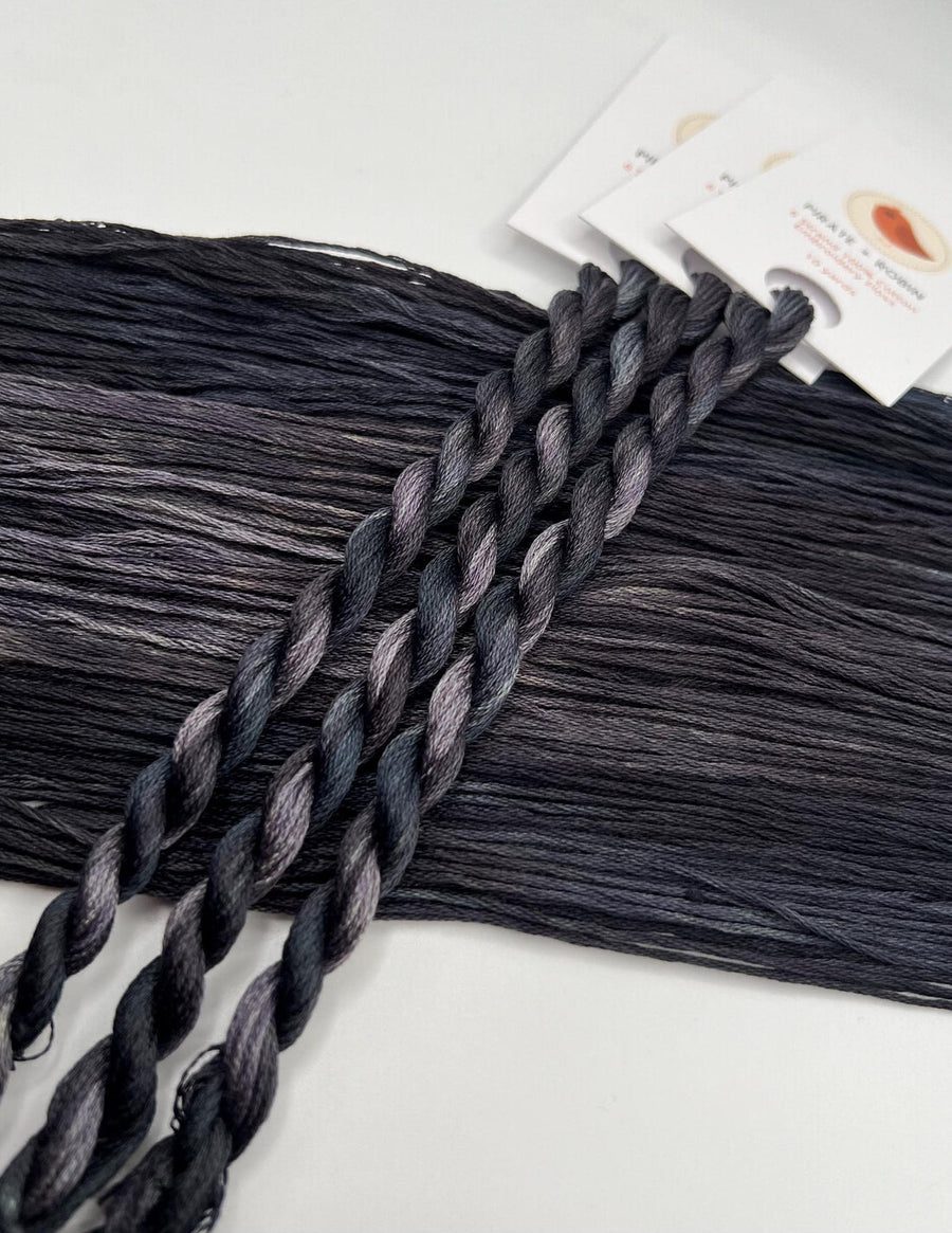Gray braided thread skeins on a white background with a product packaging.