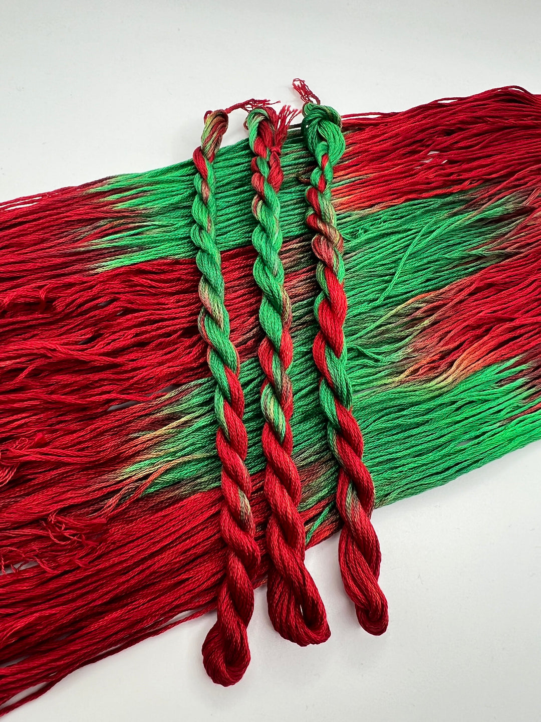 Red and green braided skeins of thread on a white background