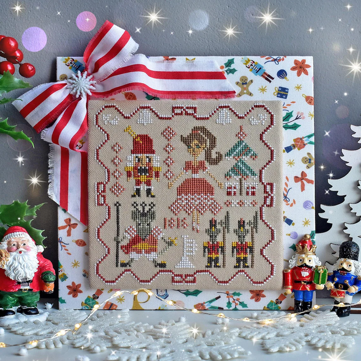 Cross-stitched Nutcracker scene with decorative ribbon and Christmas-themed decorations.