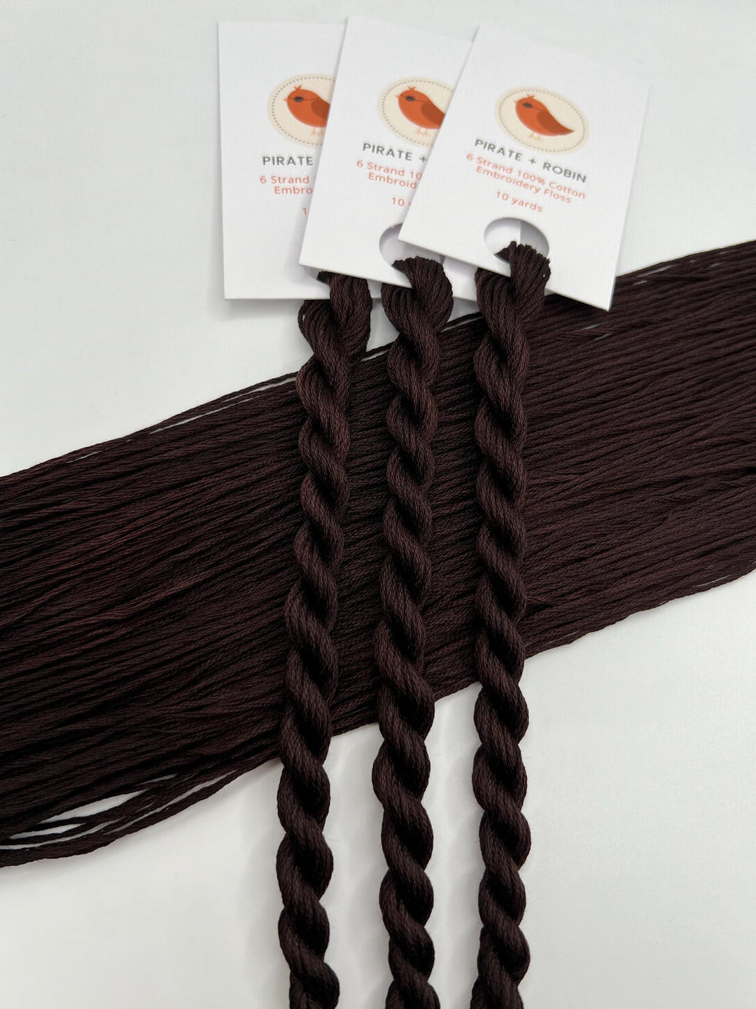 Three braided hair extensions with tags on a white background