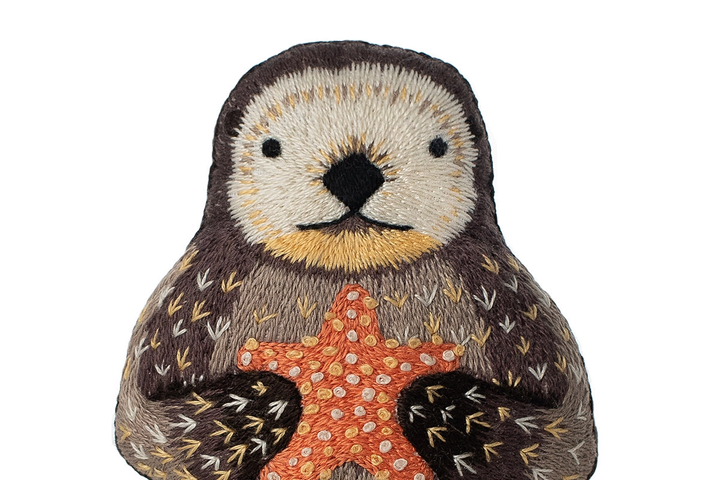 Embroidered patch of an owl holding a starfish on a white background
