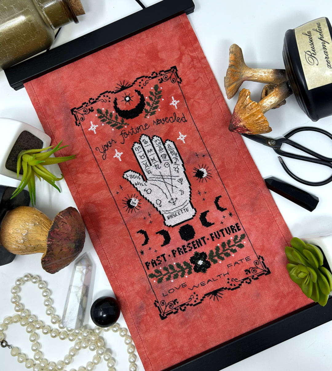 Red tarot card with black illustrations on a white background with mystical items.