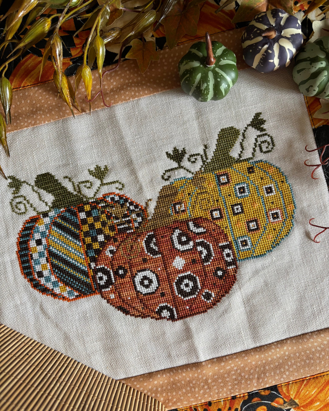 Cross-stitched pumpkins on fabric with a textured surface