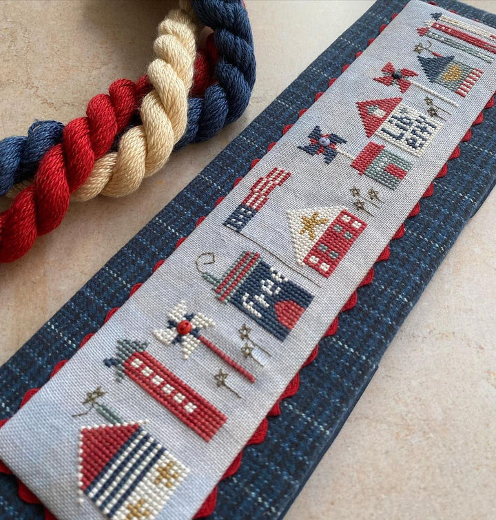 Cross-stitched fabric with nautical-themed designs on a textured surface