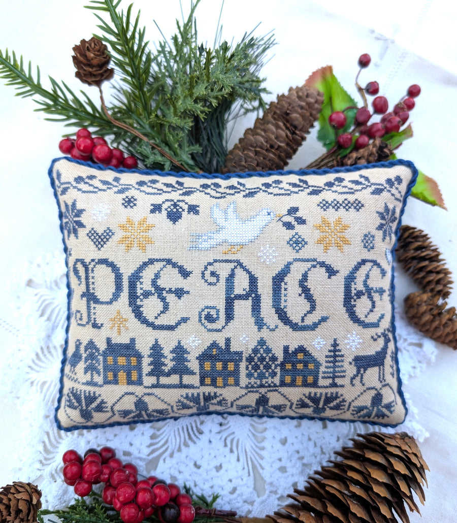 Decorative pillow with 'PEACE' text surrounded by Christmas decorations on a white background